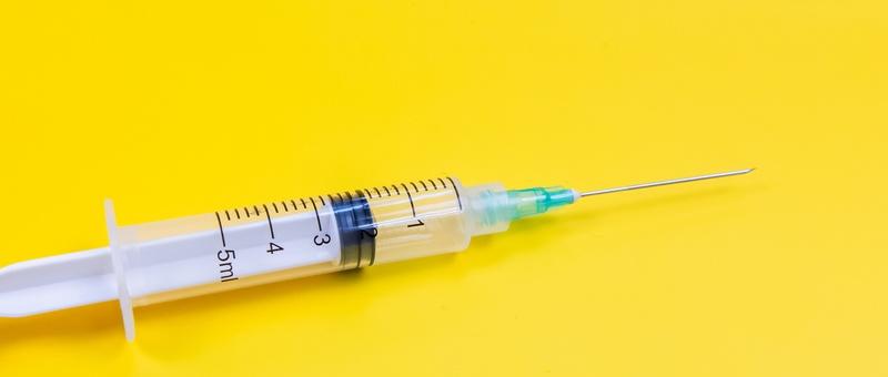 Syringe against yellow background.